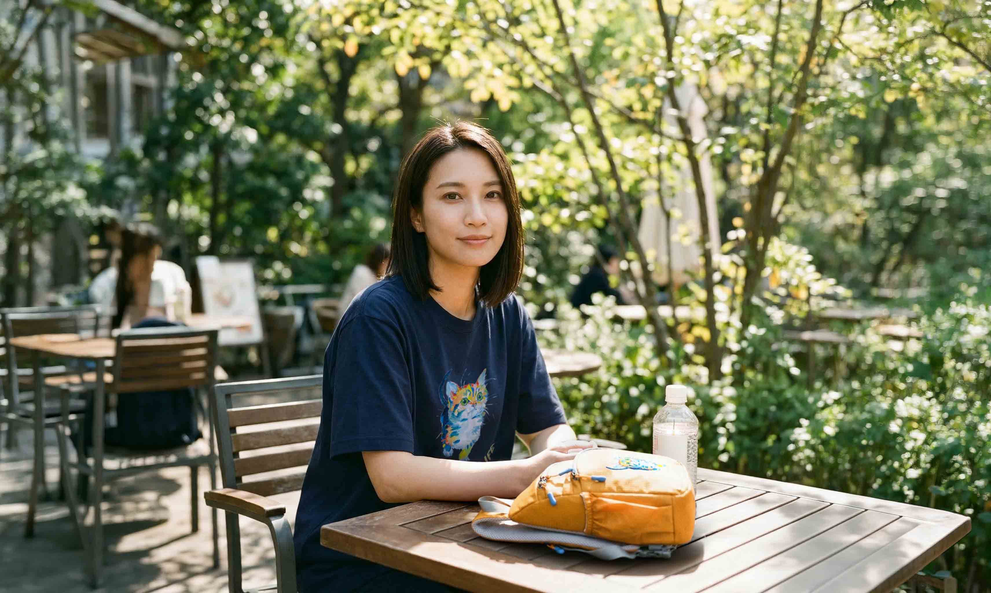 公園のベンチでランチを楽しむ女性・NEKONIWAマイ柄のNEKONI SLING