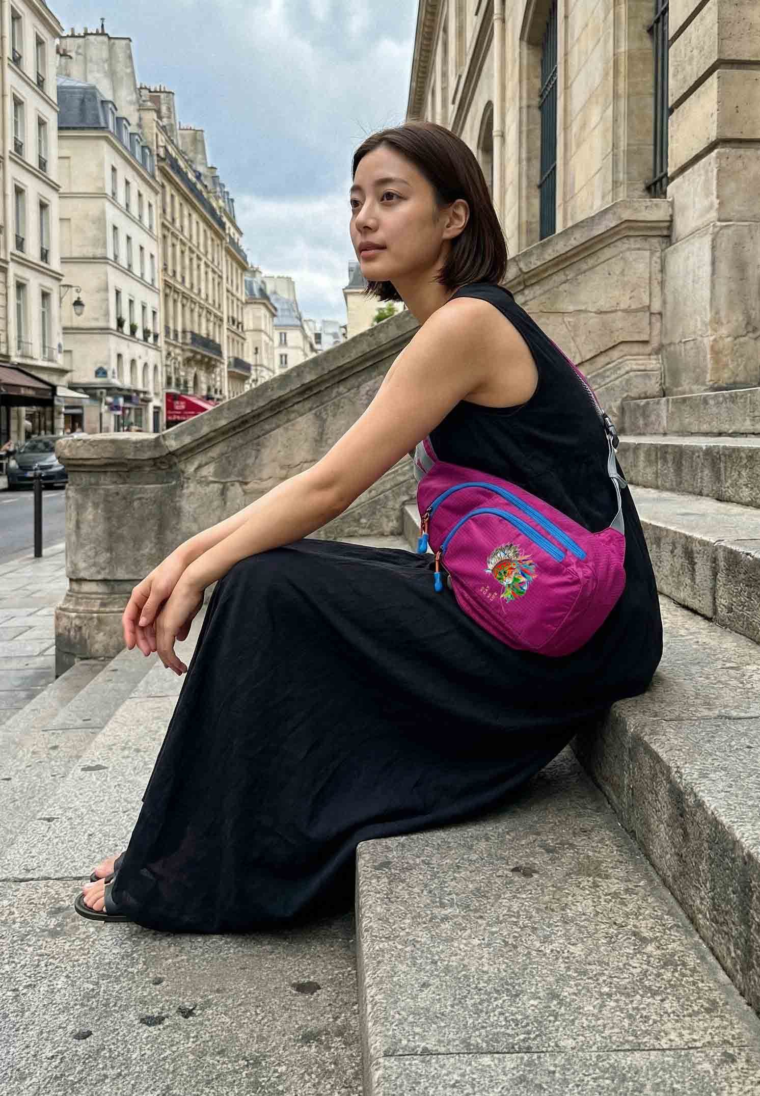 パリの街角で階段に座る黒ドレスの女性・ポップピンクのNEKONI SLINGバッグ
